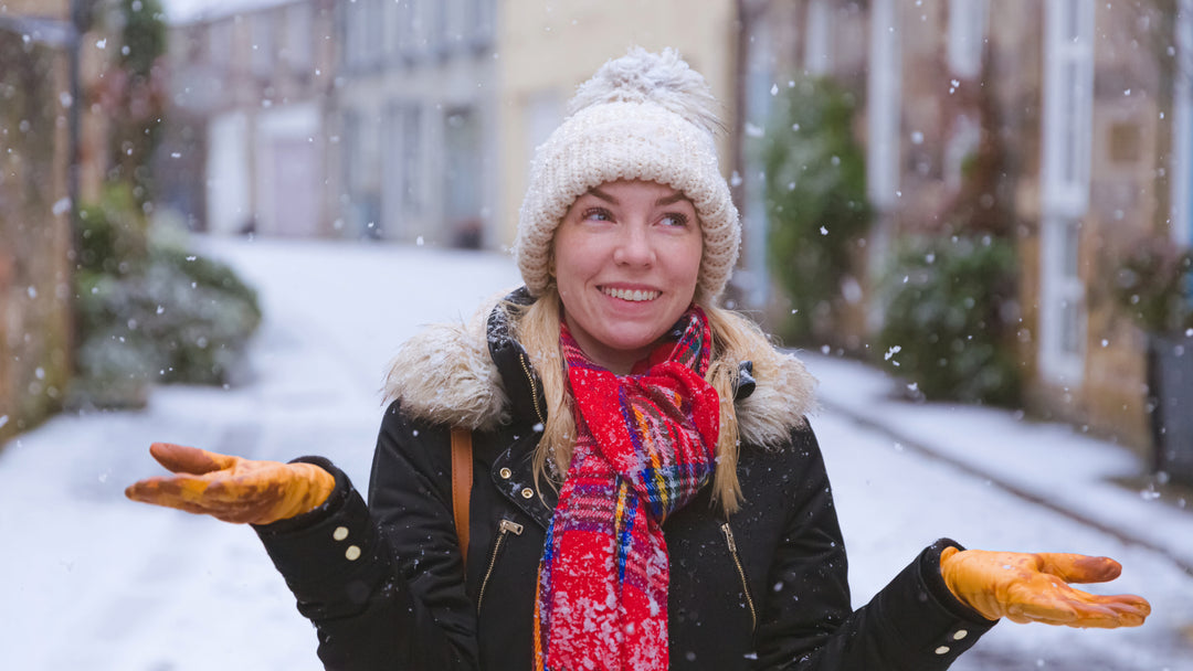 Vrouw in sneeuw met handschoenen en muts